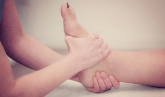 Zwei Hände einer Person, die den Fuß einer anderen Person massieren